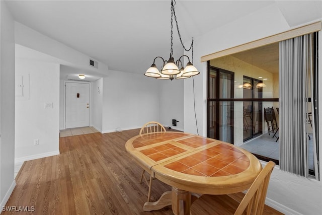 dining space with hardwood / wood-style flooring and a chandelier