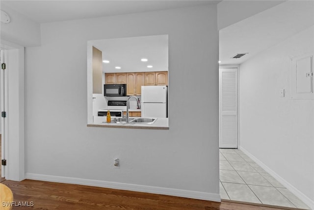 kitchen with stainless steel electric range oven, sink, white refrigerator, electric panel, and light brown cabinets