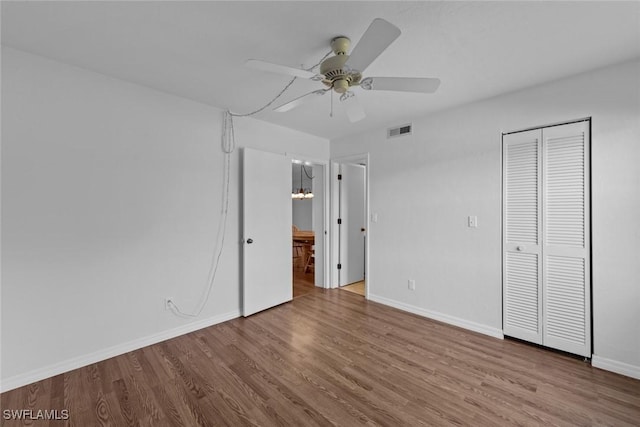 unfurnished bedroom with connected bathroom, hardwood / wood-style flooring, a closet, and ceiling fan