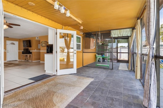 unfurnished sunroom with track lighting and ceiling fan