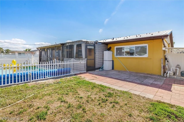 exterior space featuring a front yard, a patio area, a sunroom, and a fenced in pool