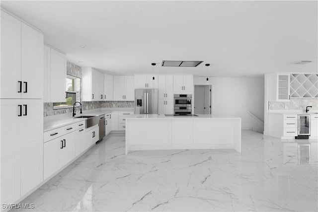 kitchen featuring white cabinetry, tasteful backsplash, appliances with stainless steel finishes, a kitchen island, and beverage cooler