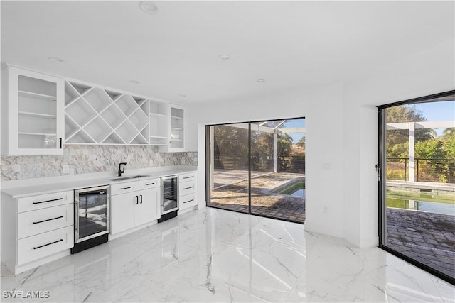 kitchen with white cabinetry, sink, wine cooler, and a healthy amount of sunlight