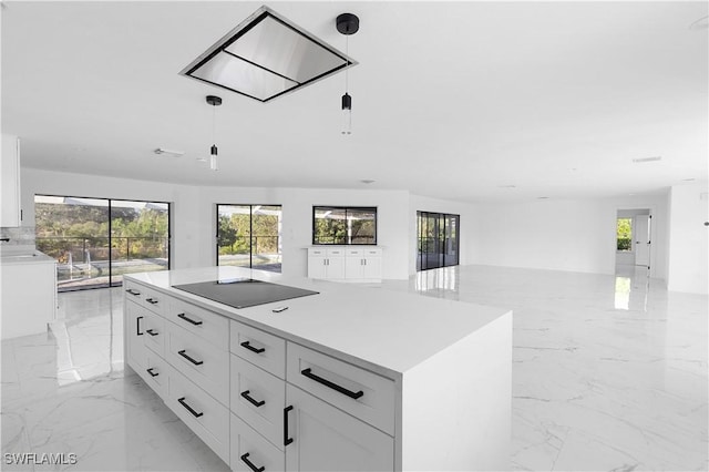 kitchen featuring white cabinetry, black electric stovetop, decorative light fixtures, and a center island