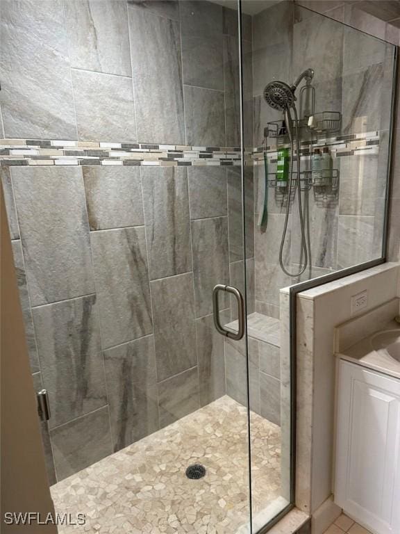 bathroom featuring tile patterned floors, a shower with door, and vanity