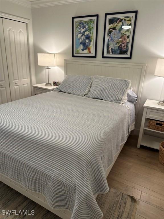 bedroom featuring a closet, crown molding, and wood-type flooring