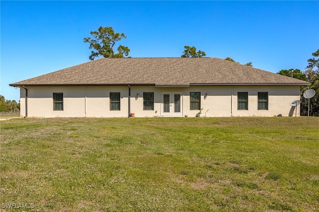 rear view of house featuring french doors, a lawn, and roof with shingles