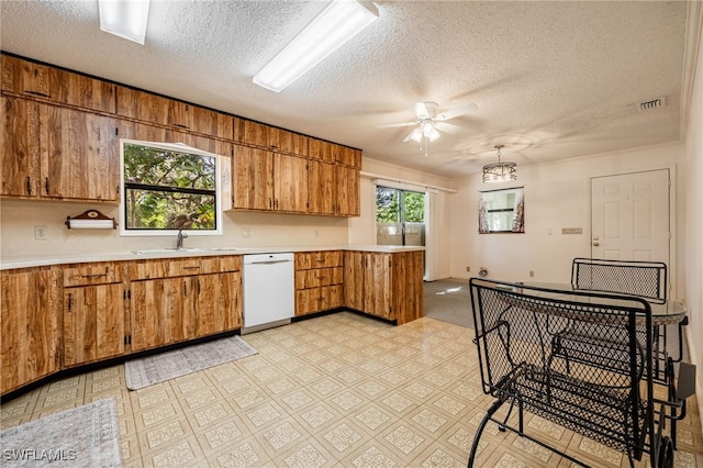 kitchen with visible vents, white dishwasher, a sink, light countertops, and brown cabinets