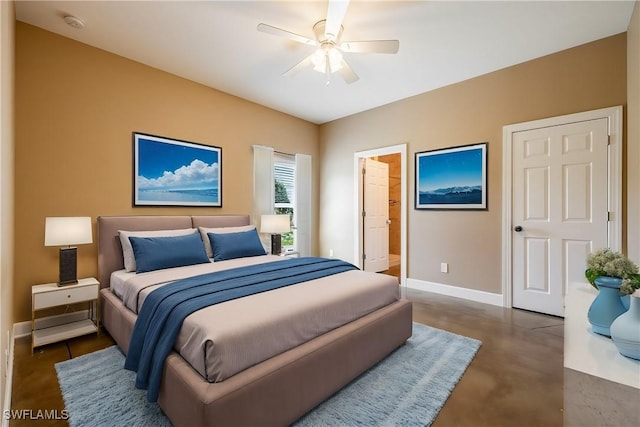 bedroom with ceiling fan, connected bathroom, baseboards, and finished concrete floors