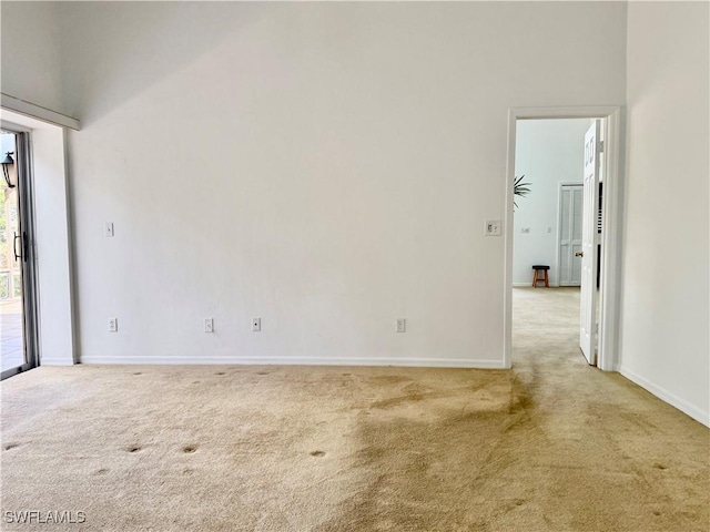 unfurnished room featuring a towering ceiling and light carpet