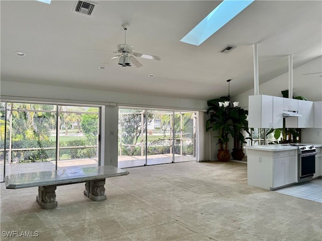 unfurnished living room featuring light carpet, a skylight, high vaulted ceiling, and ceiling fan