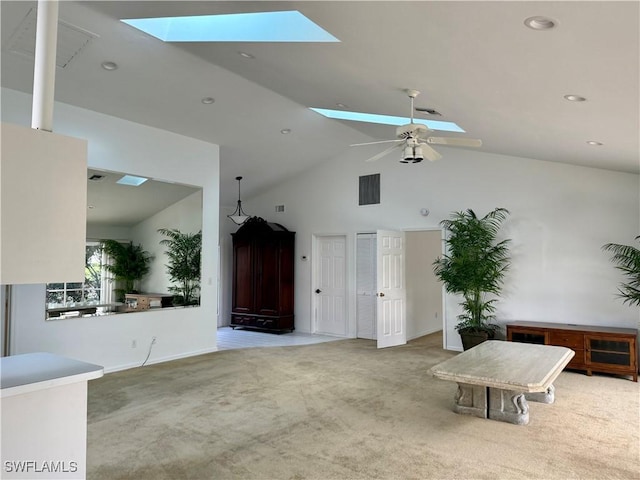 unfurnished living room with ceiling fan, light colored carpet, a skylight, and high vaulted ceiling