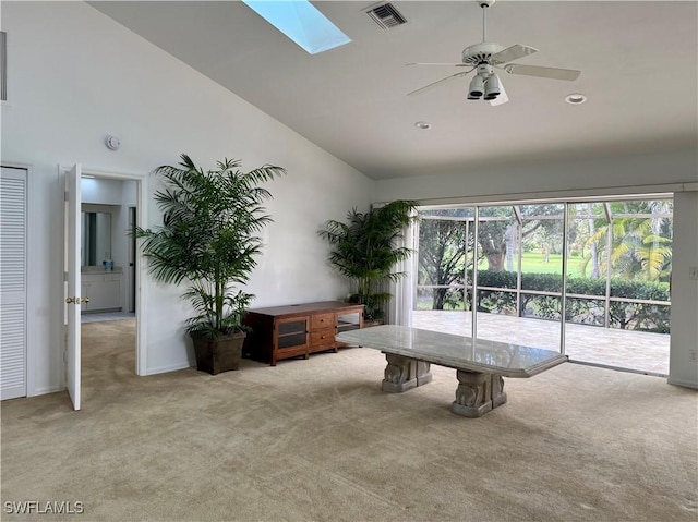 interior space featuring ceiling fan, light colored carpet, high vaulted ceiling, and a skylight