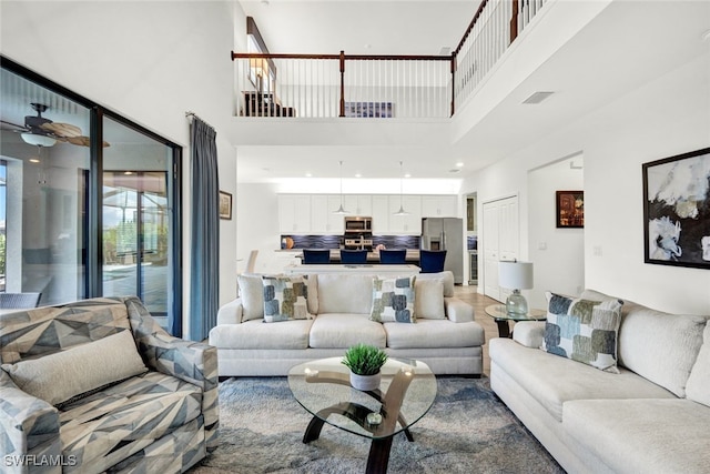 living room featuring ceiling fan and a high ceiling