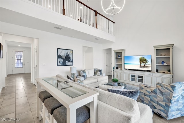 tiled living room featuring a towering ceiling and a chandelier