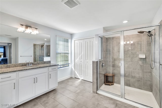 bathroom featuring vanity, a shower with shower door, and tile patterned flooring