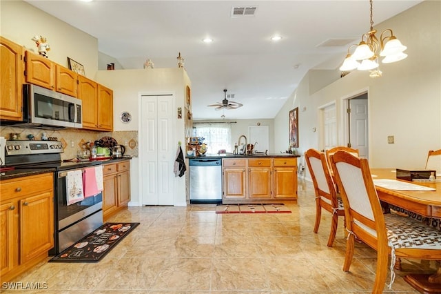 kitchen with ceiling fan with notable chandelier, tasteful backsplash, lofted ceiling, sink, and stainless steel appliances