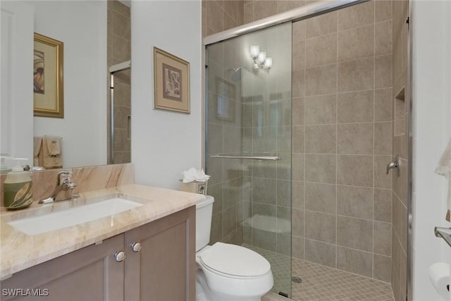 bathroom featuring vanity, a shower with shower door, and toilet