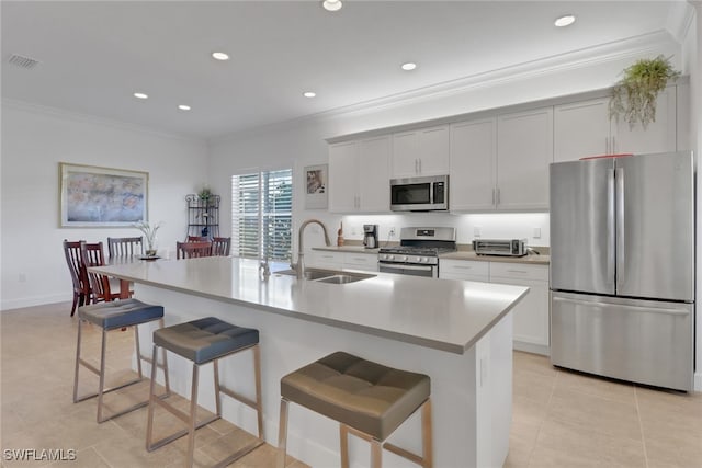 kitchen featuring appliances with stainless steel finishes, sink, a center island with sink, and a kitchen bar