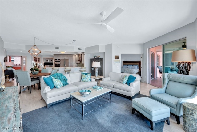 living room featuring ceiling fan with notable chandelier and hardwood / wood-style floors