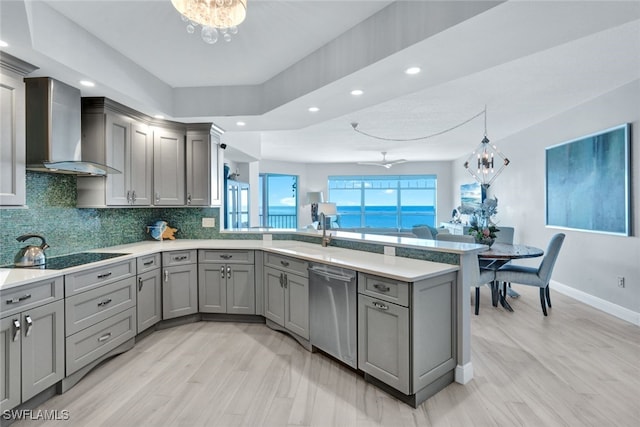 kitchen featuring sink, gray cabinets, stainless steel dishwasher, kitchen peninsula, and wall chimney exhaust hood