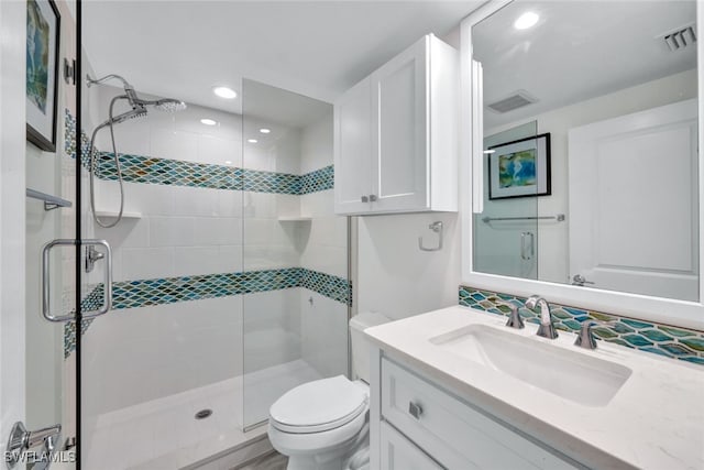 bathroom featuring vanity, an enclosed shower, and toilet