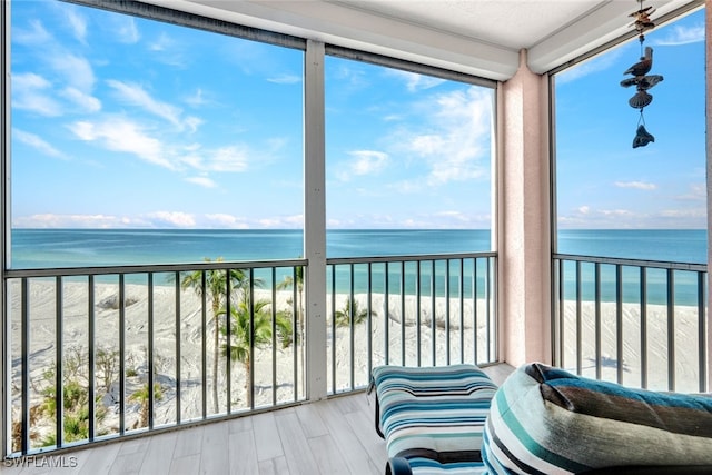 sunroom / solarium featuring a beach view and a water view