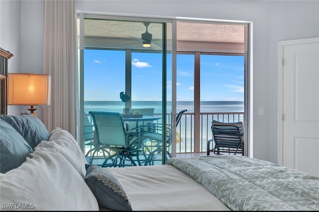 bedroom with multiple windows, a water view, and access to outside