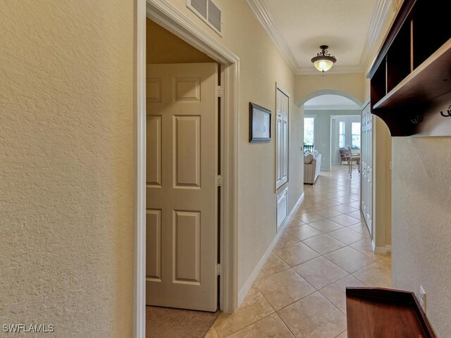 hall with ornamental molding and light tile patterned floors