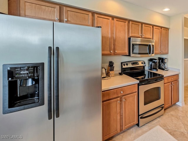 kitchen with light tile patterned floors, recessed lighting, light countertops, appliances with stainless steel finishes, and brown cabinetry