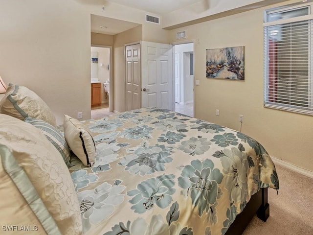 bedroom with light colored carpet, connected bathroom, and a closet