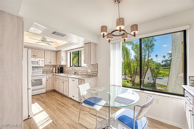 kitchen featuring sink, hanging light fixtures, light hardwood / wood-style flooring, a raised ceiling, and white appliances