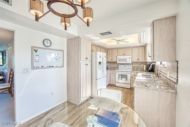 kitchen with sink, white appliances, tasteful backsplash, light brown cabinetry, and a raised ceiling