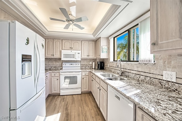 kitchen featuring sink, a tray ceiling, crown molding, white appliances, and light hardwood / wood-style flooring