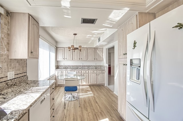 kitchen featuring dishwasher, hanging light fixtures, white refrigerator with ice dispenser, light stone counters, and light hardwood / wood-style flooring