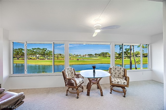 sunroom / solarium featuring ceiling fan and a water view