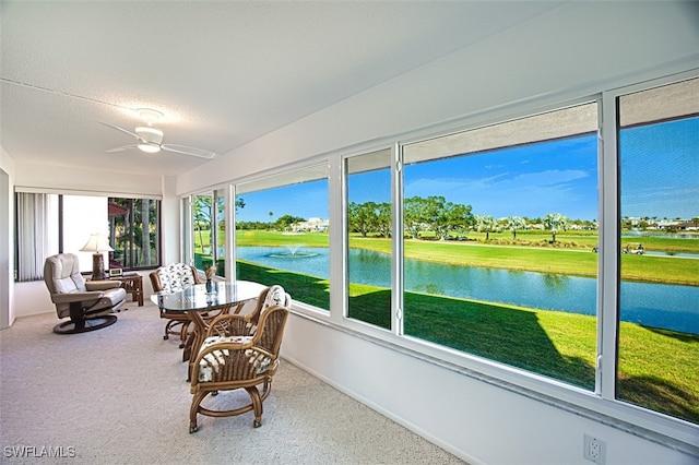 sunroom / solarium with a water view and ceiling fan