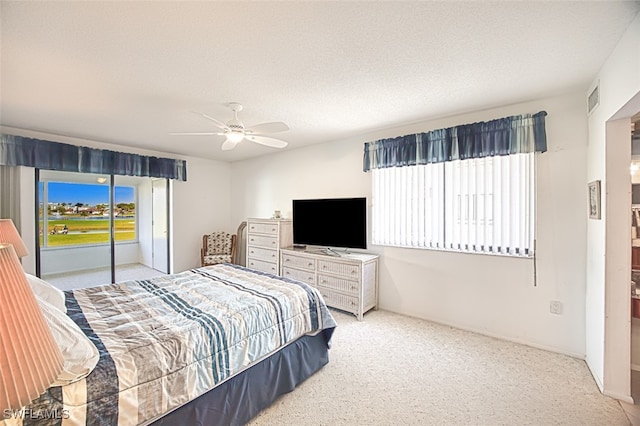 carpeted bedroom with ceiling fan and a textured ceiling