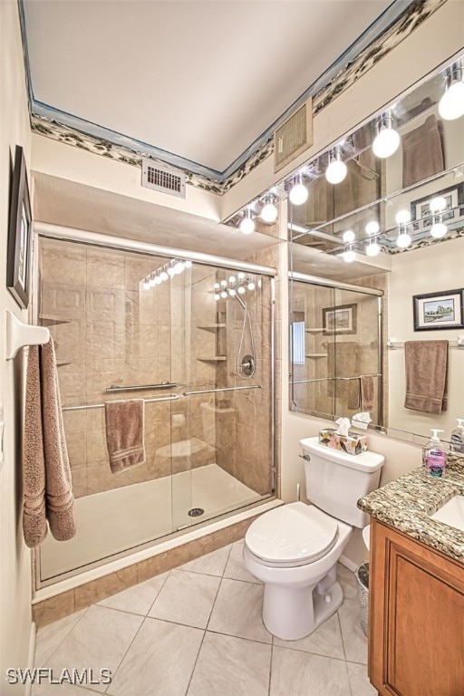 bathroom with a shower with door, vanity, tile patterned flooring, and toilet