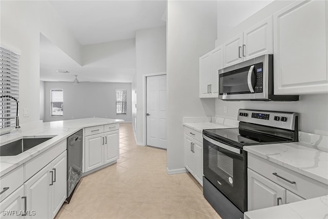 kitchen with light stone counters, stainless steel appliances, sink, and white cabinets