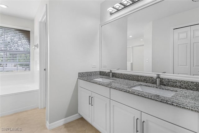 bathroom with a tub to relax in, tile patterned floors, and vanity