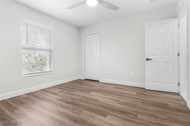 unfurnished bedroom featuring wood-type flooring, a closet, and ceiling fan