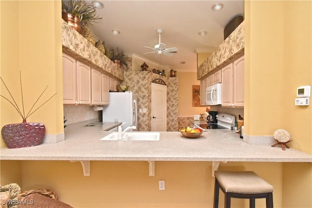 kitchen with white appliances, a peninsula, a kitchen breakfast bar, and a sink