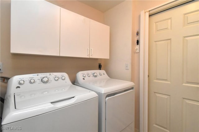 clothes washing area featuring separate washer and dryer and cabinet space