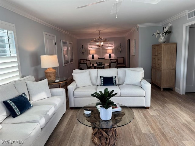 living room with hardwood / wood-style flooring, ceiling fan with notable chandelier, and ornamental molding