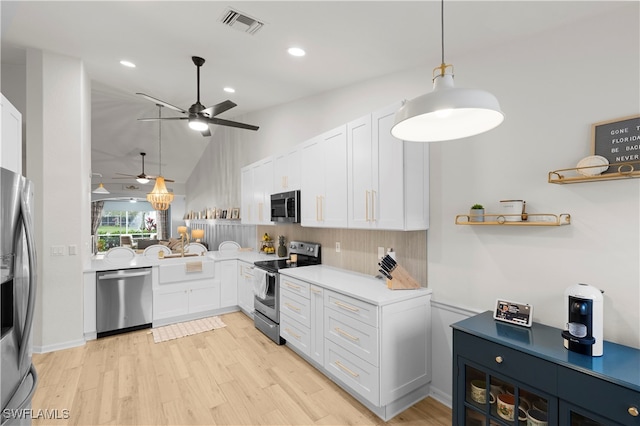 kitchen featuring lofted ceiling, light hardwood / wood-style flooring, appliances with stainless steel finishes, hanging light fixtures, and white cabinets