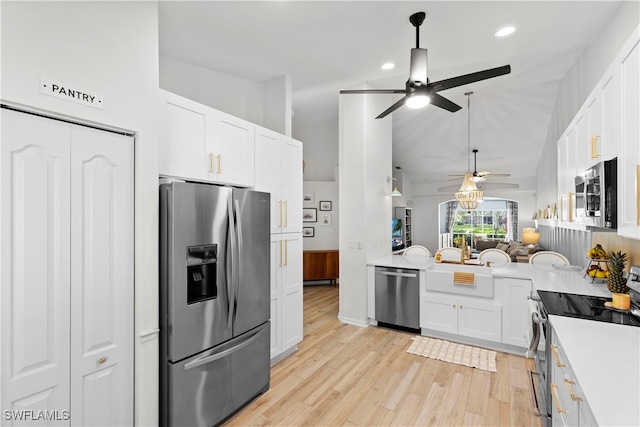 kitchen featuring vaulted ceiling, light hardwood / wood-style flooring, ceiling fan, stainless steel appliances, and white cabinets