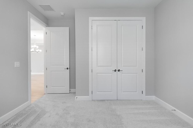 26930 Lark Ct, Punta Gorda, FL 33955 - unfurnished bedroom featuring light carpet, baseboards, a closet, and a chandelier
