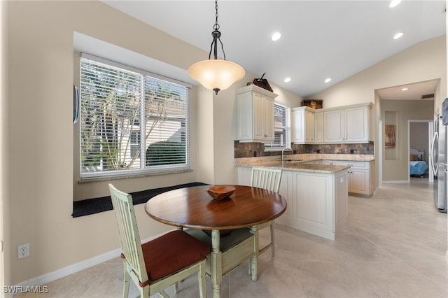 tiled dining area with lofted ceiling and sink