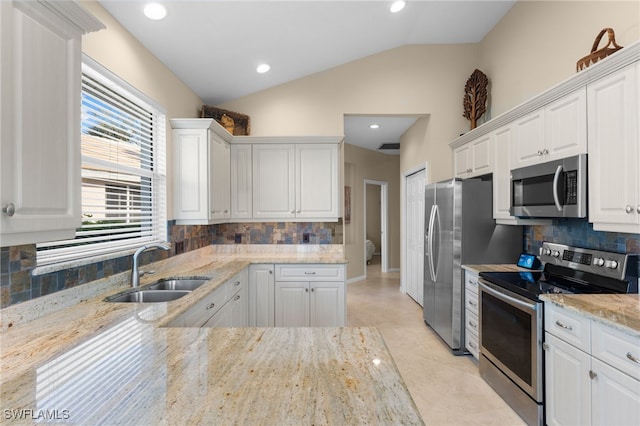 kitchen with appliances with stainless steel finishes, sink, white cabinets, and light stone counters